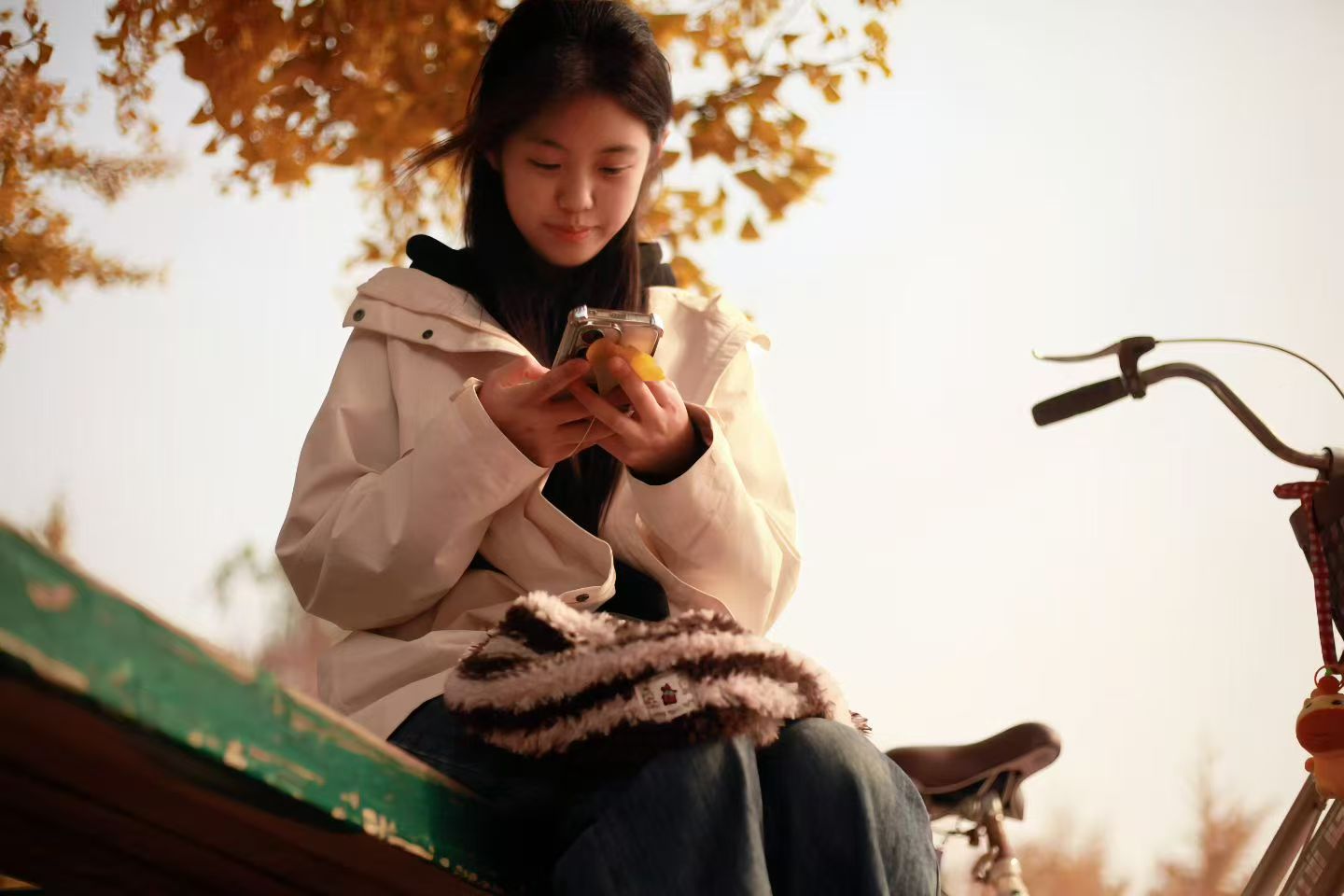 米外套与毛绒挎包透着暖意，专注的侧脸与秋日阳光构成宁静画面。这一刻，师院的秋日不仅有诗意，更有着属于每个人的闲适时光。