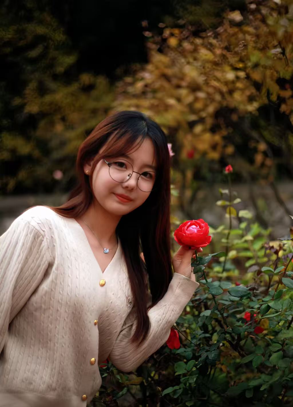 她手握一朵红月季，与师院的秋天温柔相拥。镜片后是沉静而明亮的眼眸，人比花娇定格了秋日校园里，一份独属于学子的诗意与安宁。
