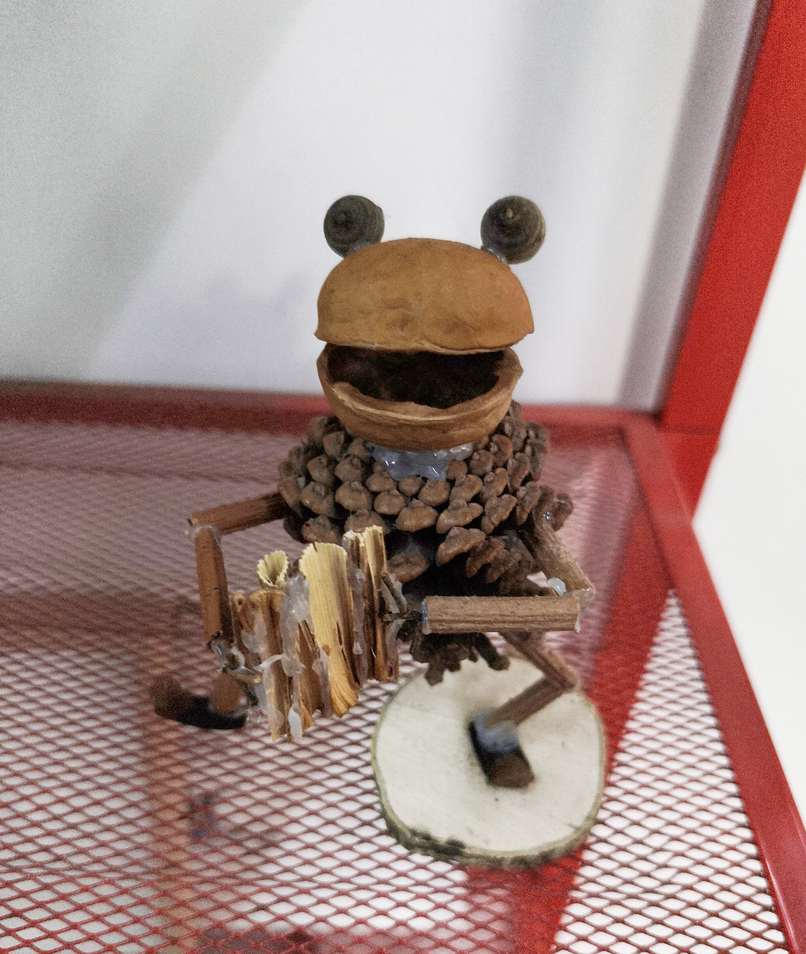 取金陵秋野的松果、核桃壳等自然物，塑成俏皮乐手，保留天然肌理与原生形态，不加修饰的创作，让秋的鲜活与生活意趣完美交融。