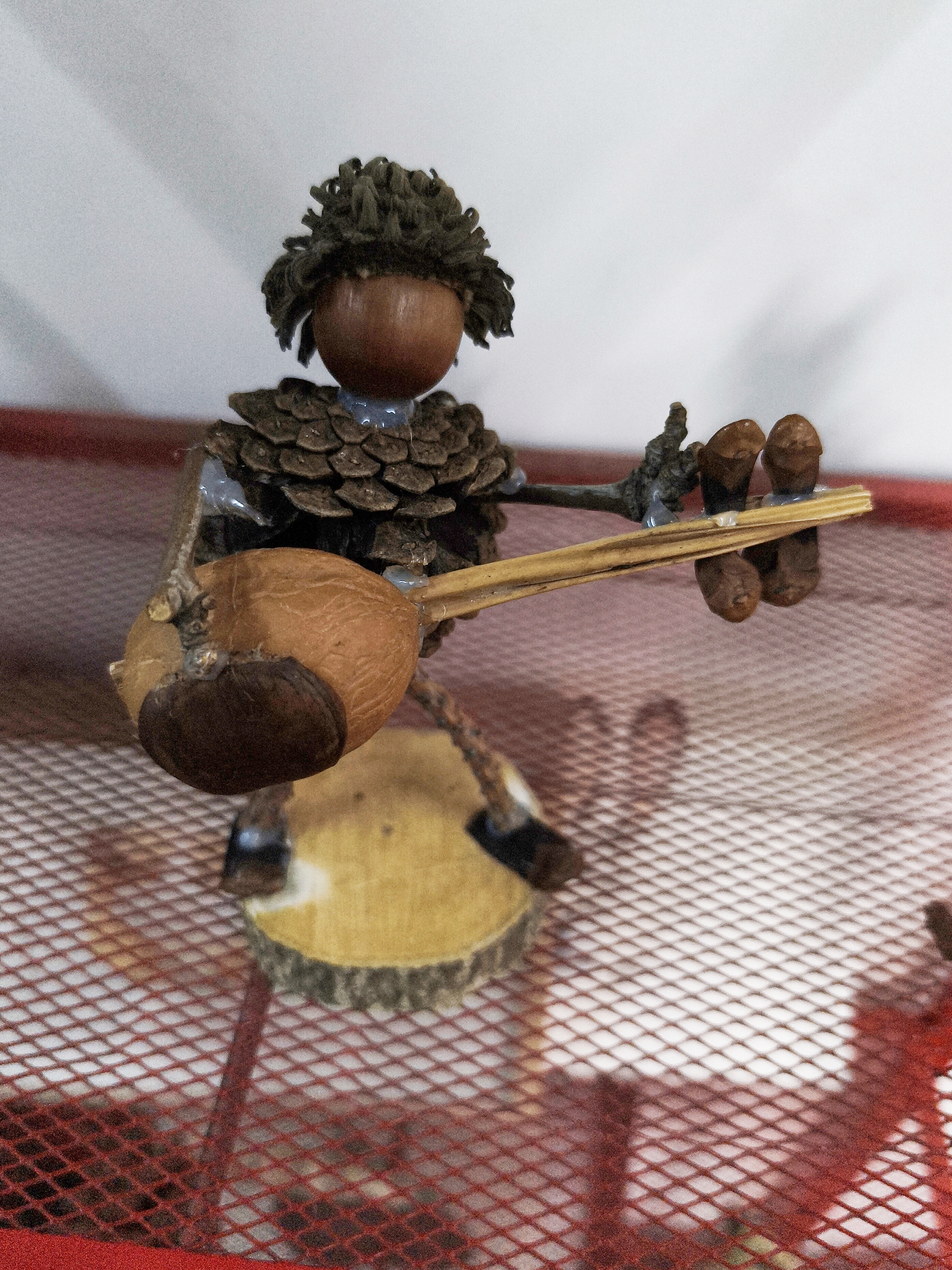 用橡果作头、松果为身，塑成持手风琴的乐手，不破坏原生形态，以自然鳞甲与纹理，奏响秋物重生的热闹协奏。