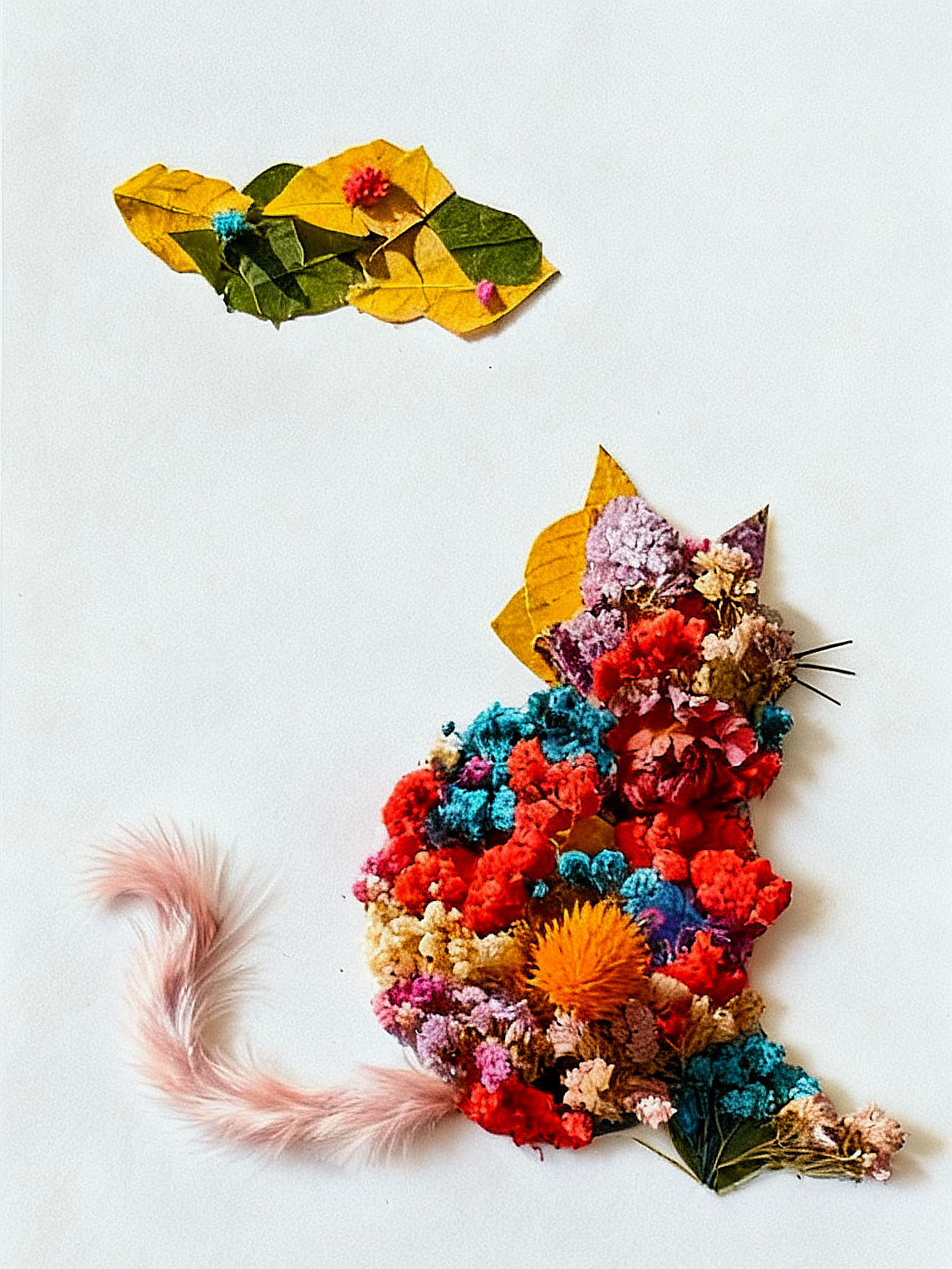 用多彩干花层层堆叠，塑造出猫咪圆润的身子，枯黄叶片剪出俏皮耳朵，粉色羽毛化作灵动尾巴，让时节的花叶成为惹人喜爱的伙伴。
