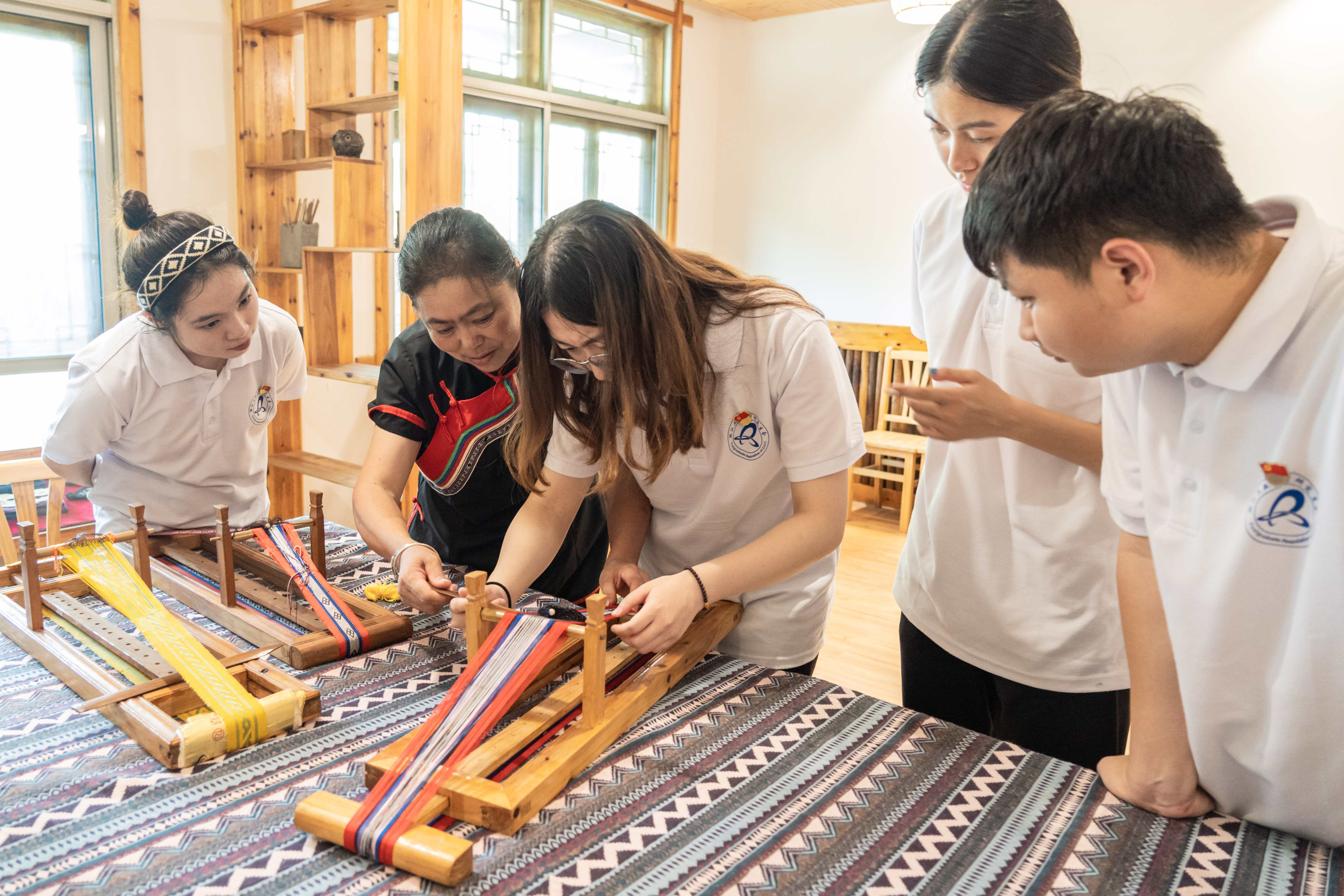 图为畲族彩带编织技艺省级非物质文化遗产传承人蓝延兰女士带领实践队体验畲族彩带编织技艺。