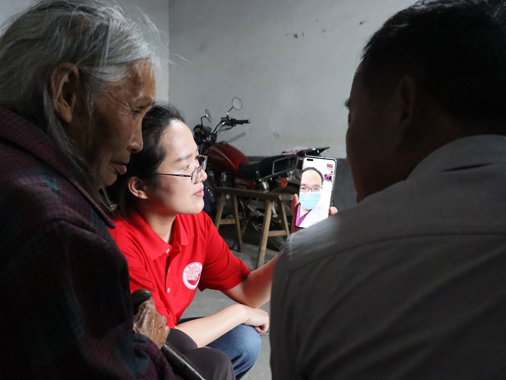 图为实践队指导老师为行动不便的老人进行连线专家问诊，将义诊送入家门。