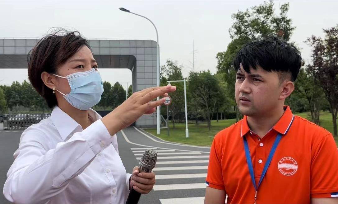 图为团队带队老师在采访讲解员以了解蔚来新能源汽车