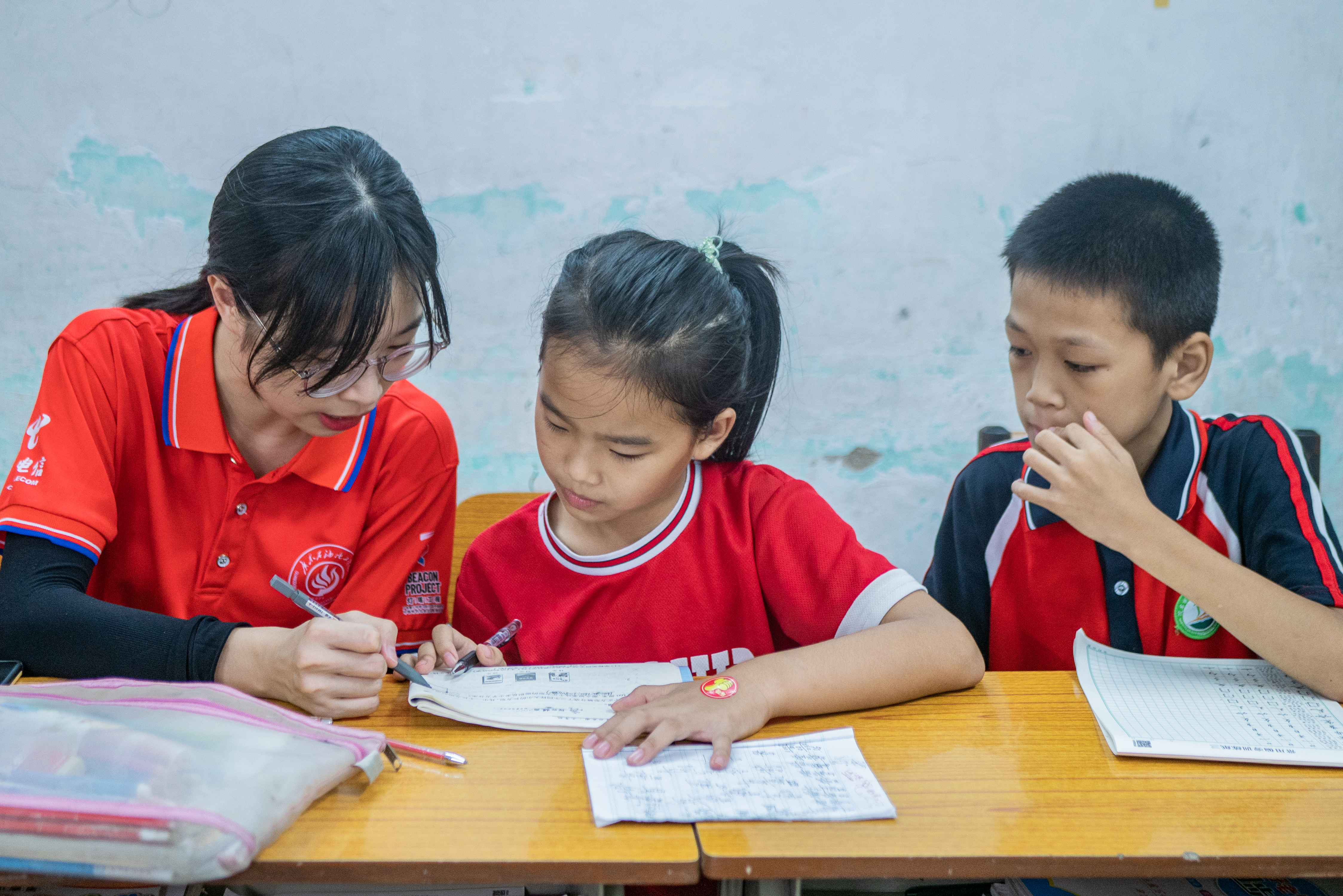图为“绿创使者”志愿服务团队为学生开设的语文朗读听写教学课堂，团队成员一对一对学生进行拼音朗读辅导。