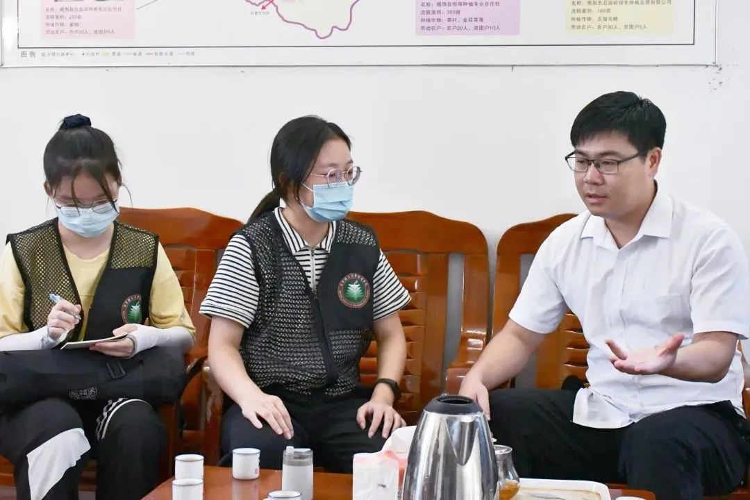 图为实践队队员向坪上镇农业部主任深入了解坪上镇“一村一品”项目。