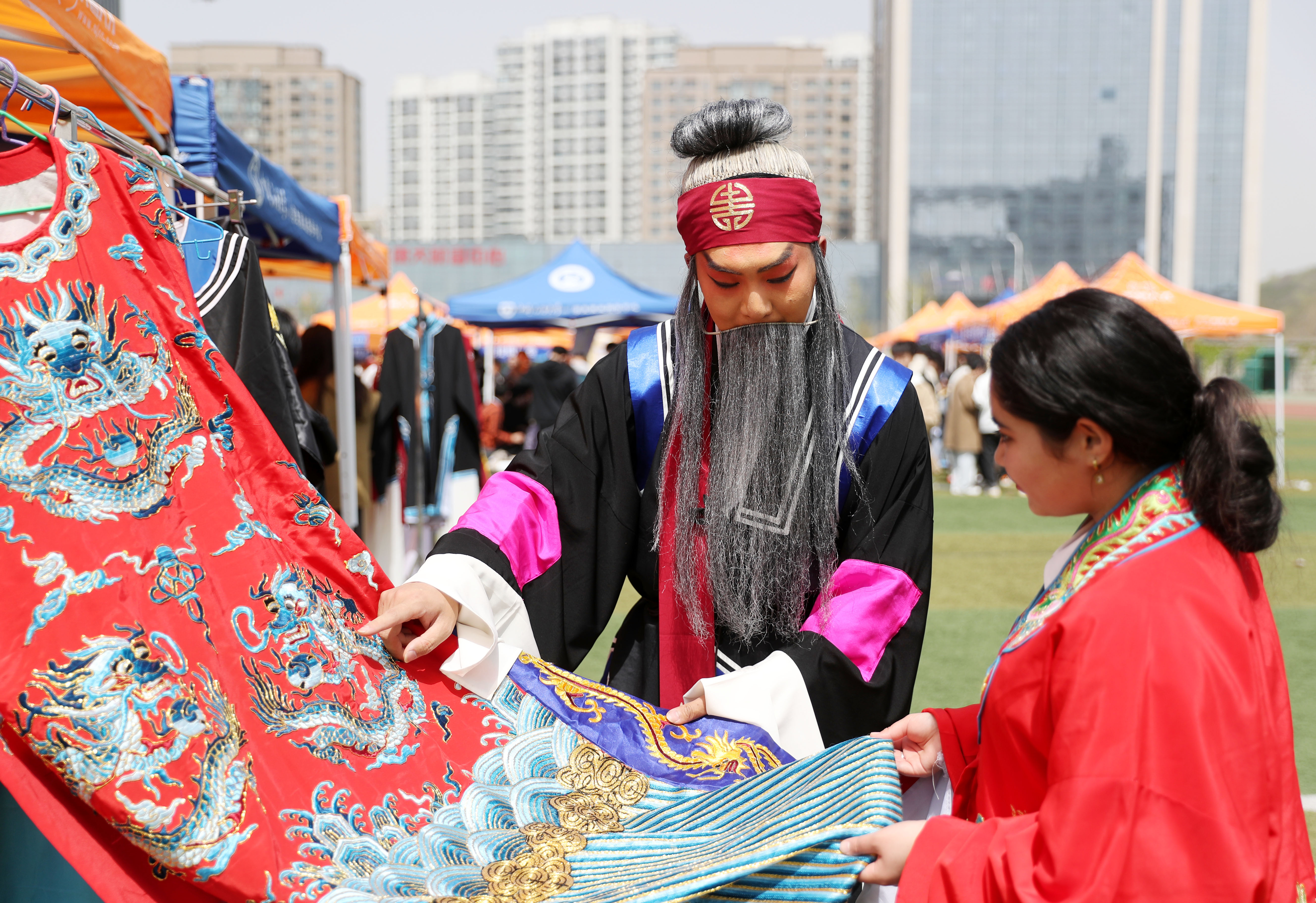 4月15日，中国石油大学（华东）韵远京剧队的队员（左）在给外国留学生介绍服饰图案的含义。（张进刚 摄）