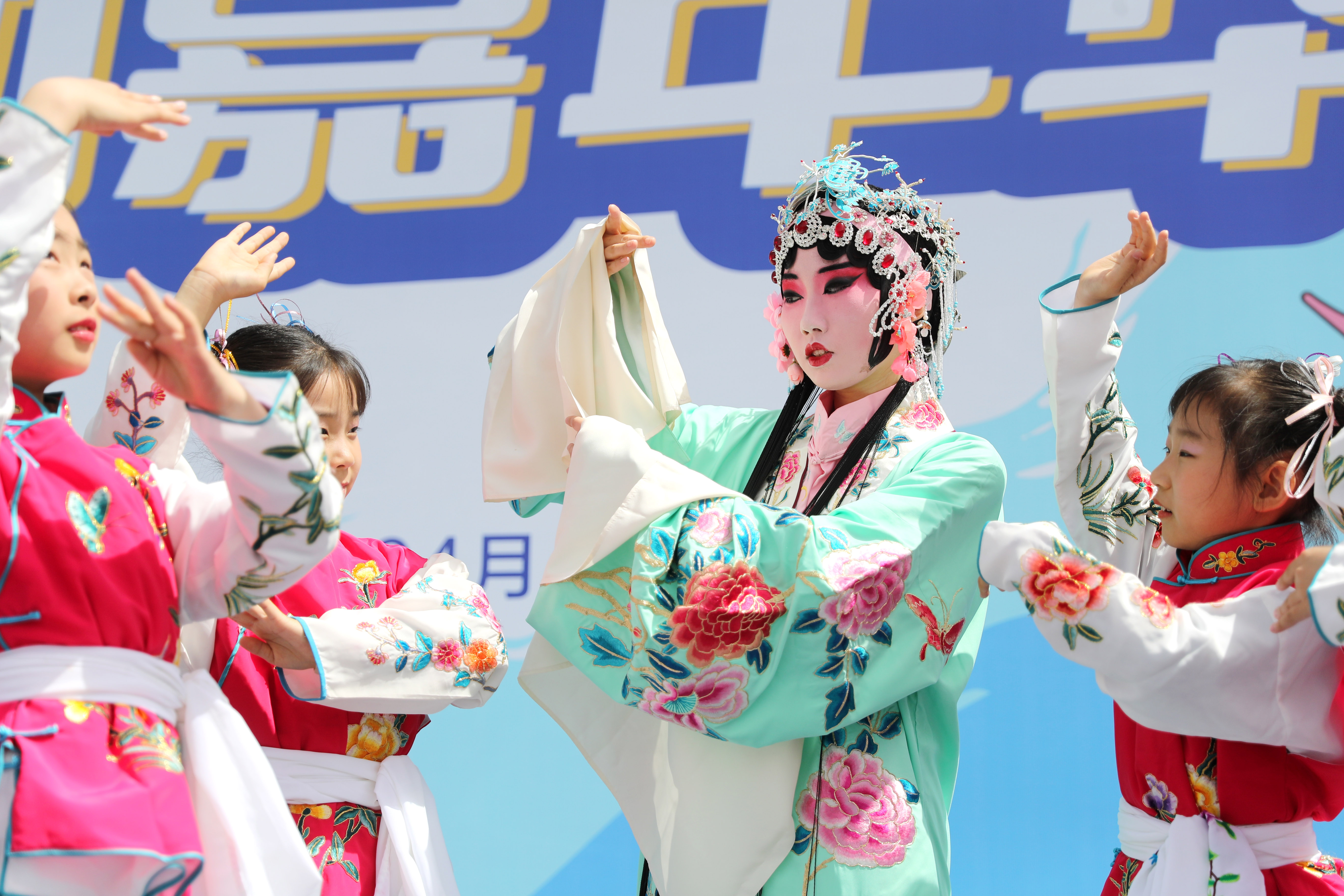 4月15日，中国石油大学（华东）韵远京剧队的队员和青岛西海岸新区珠江路小学的同学们一起进行京剧表演。（张进刚 摄）