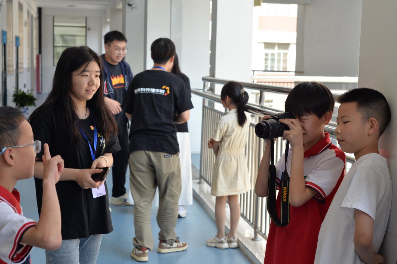图为钟宝镇小学学生在志愿者的指导下用相机记录下同学的笑脸。通讯员 阎奕璇 供图