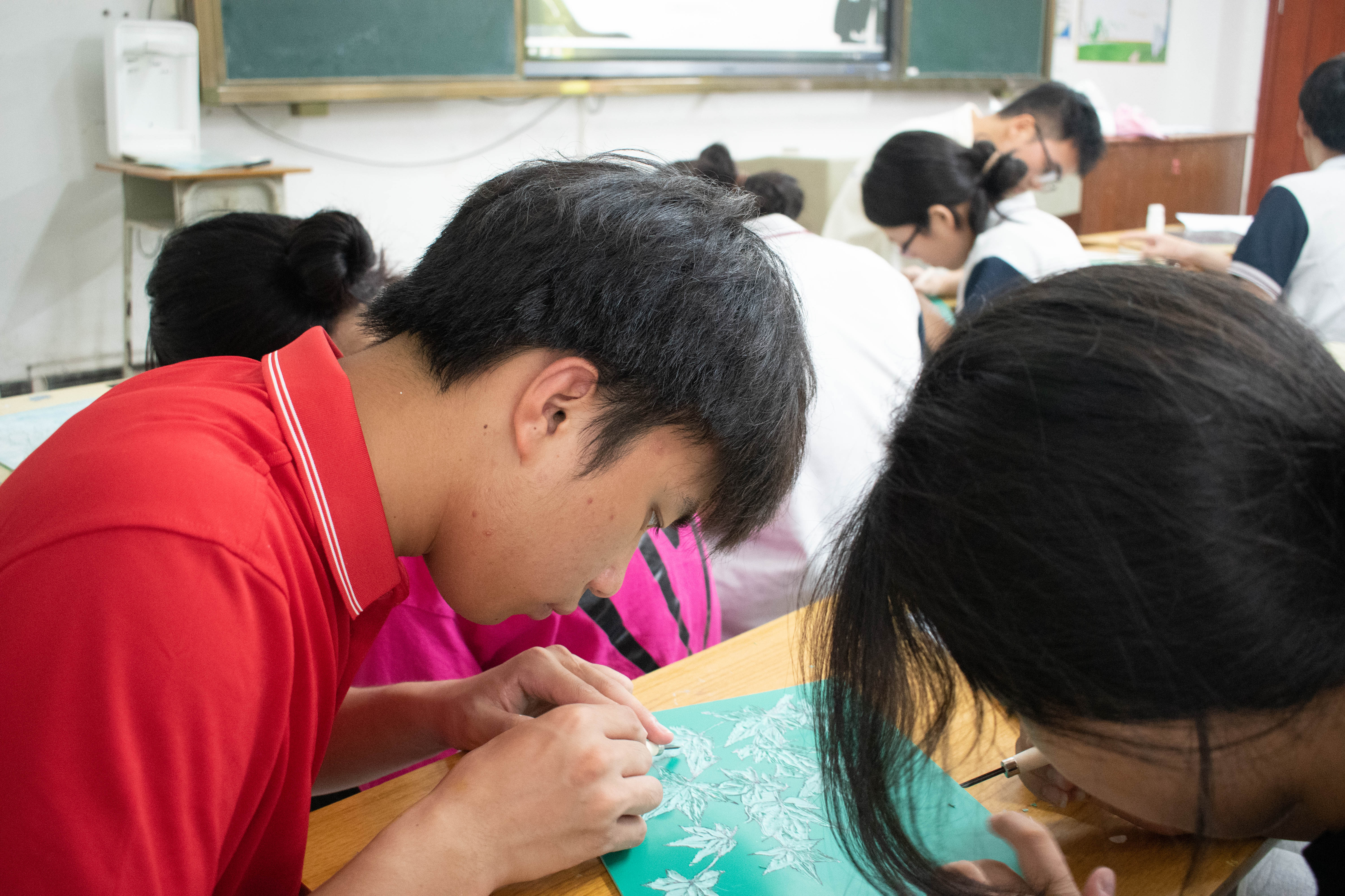 图为融媒体资助宣传实践队队员在棉洋中学教学生版刻现场。（屈泊名 供图）