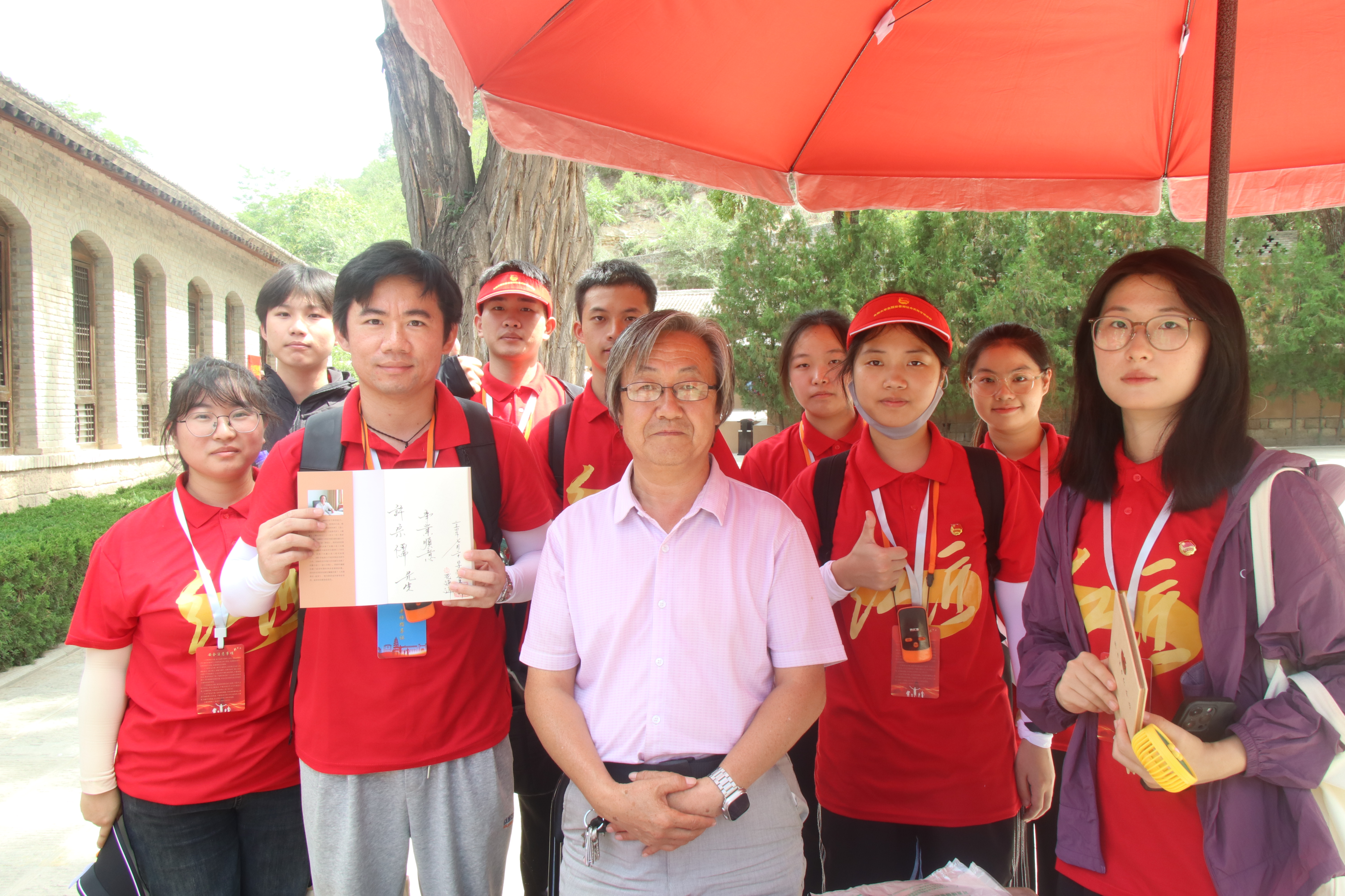 图为王家坪革命旧址著名作家花海洋先生为实践团赠书，并讲述走进延安的故事  谢梦婷摄