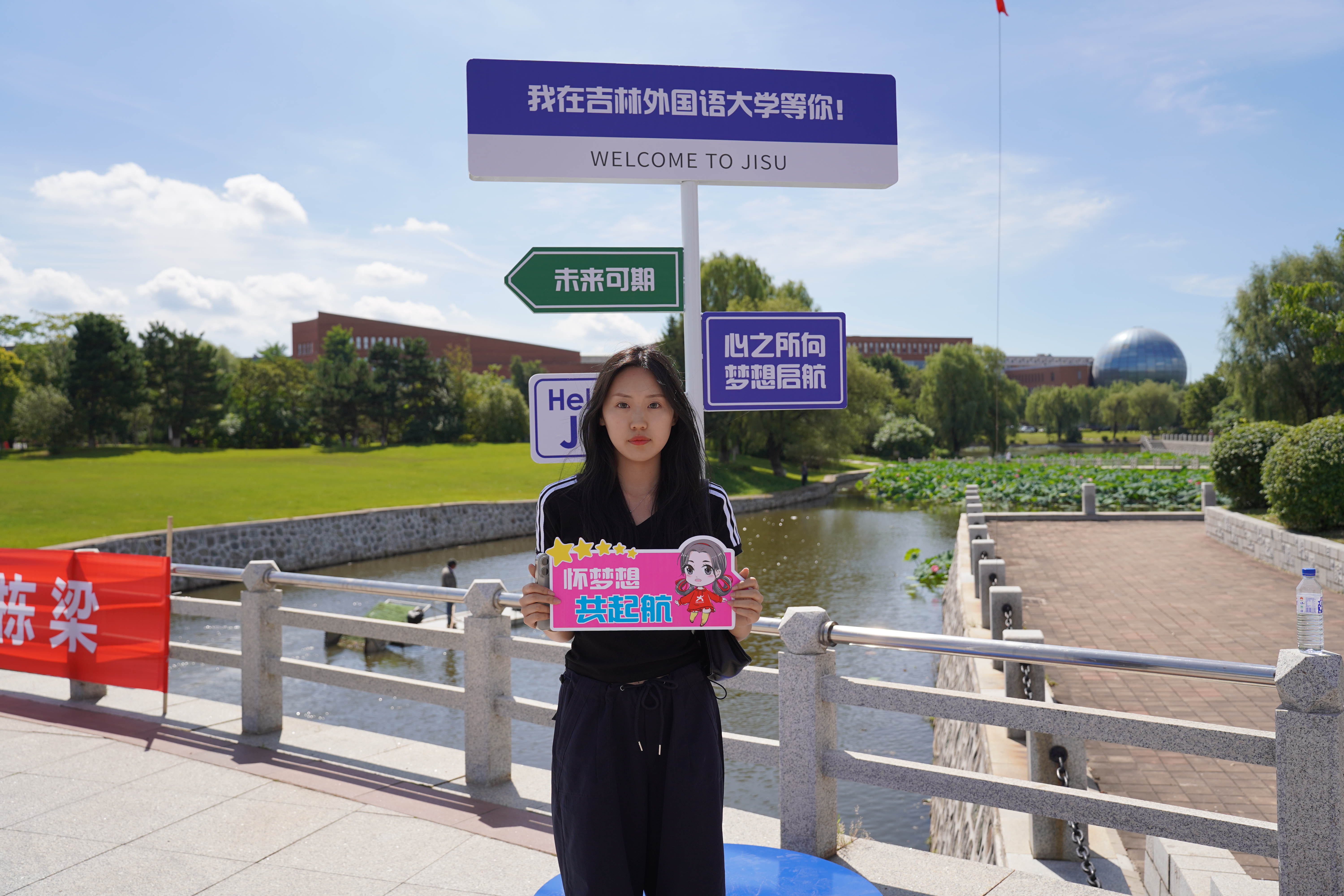 在校园桥边的“Welcome to JISU”指示牌旁