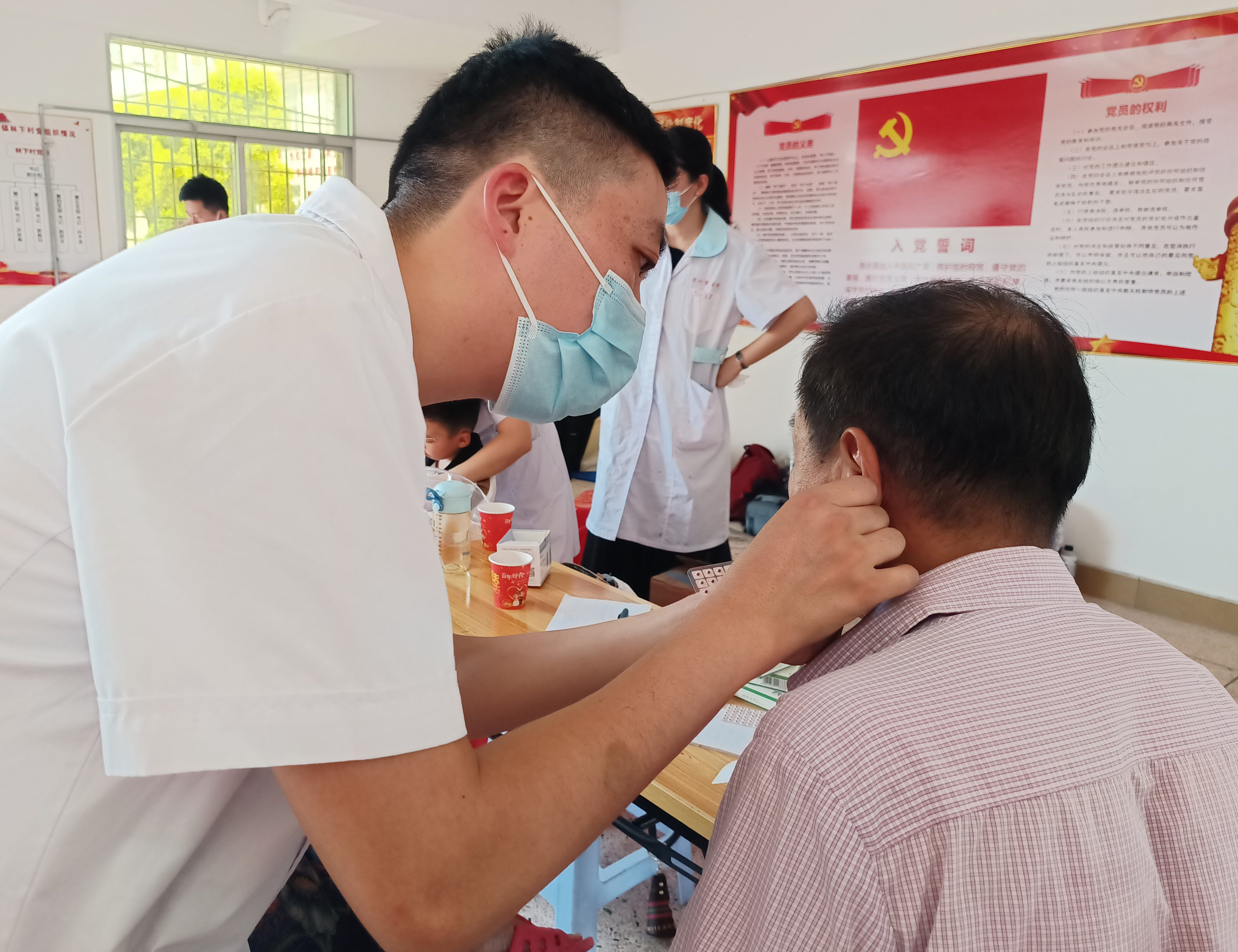 05中医科王青松医生为村民贴耳穴。（郭雯/摄）