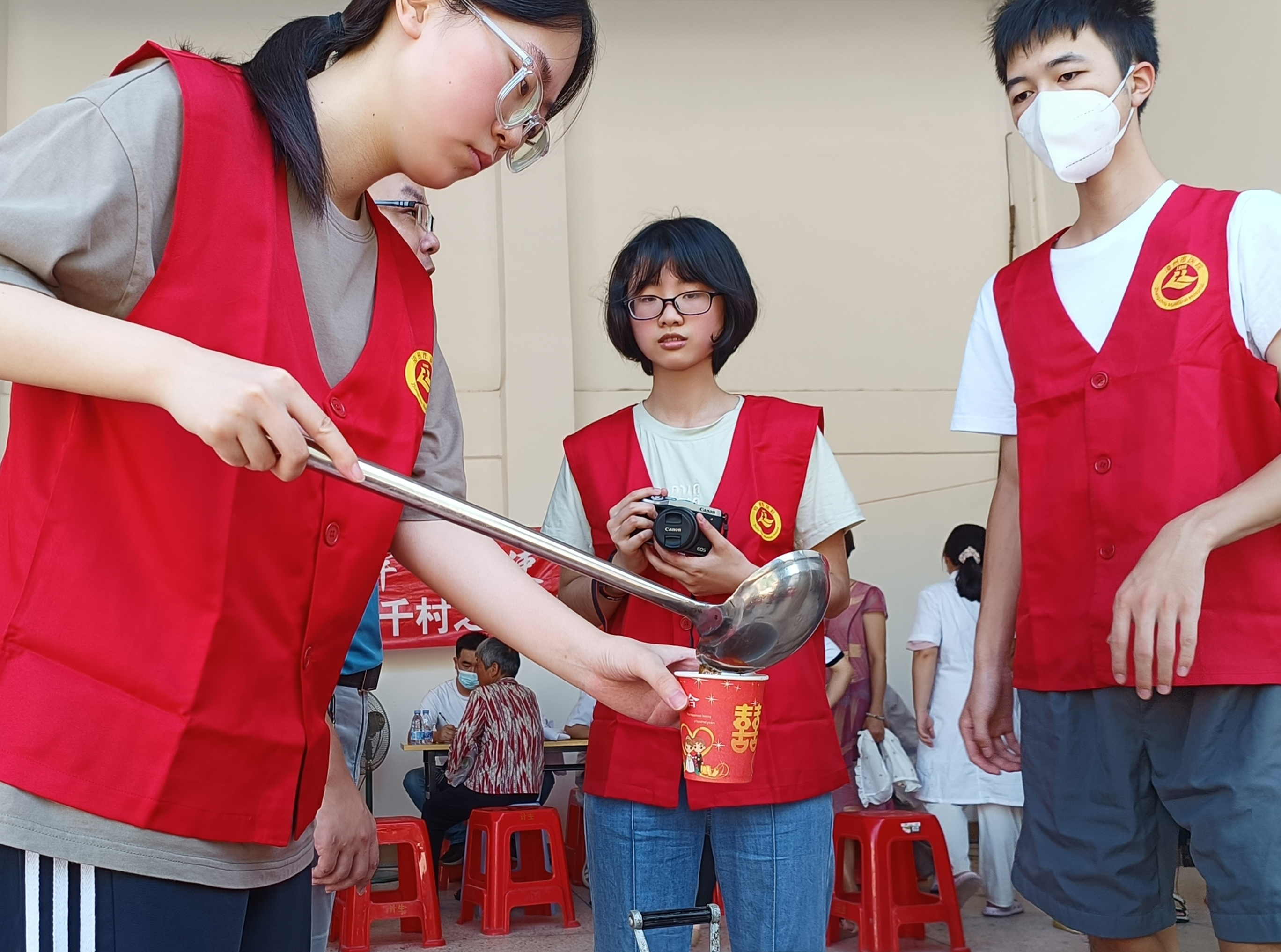 04队员蔡娜为现场医生、村民及工作人员分装解暑茶。（郭雯/摄）