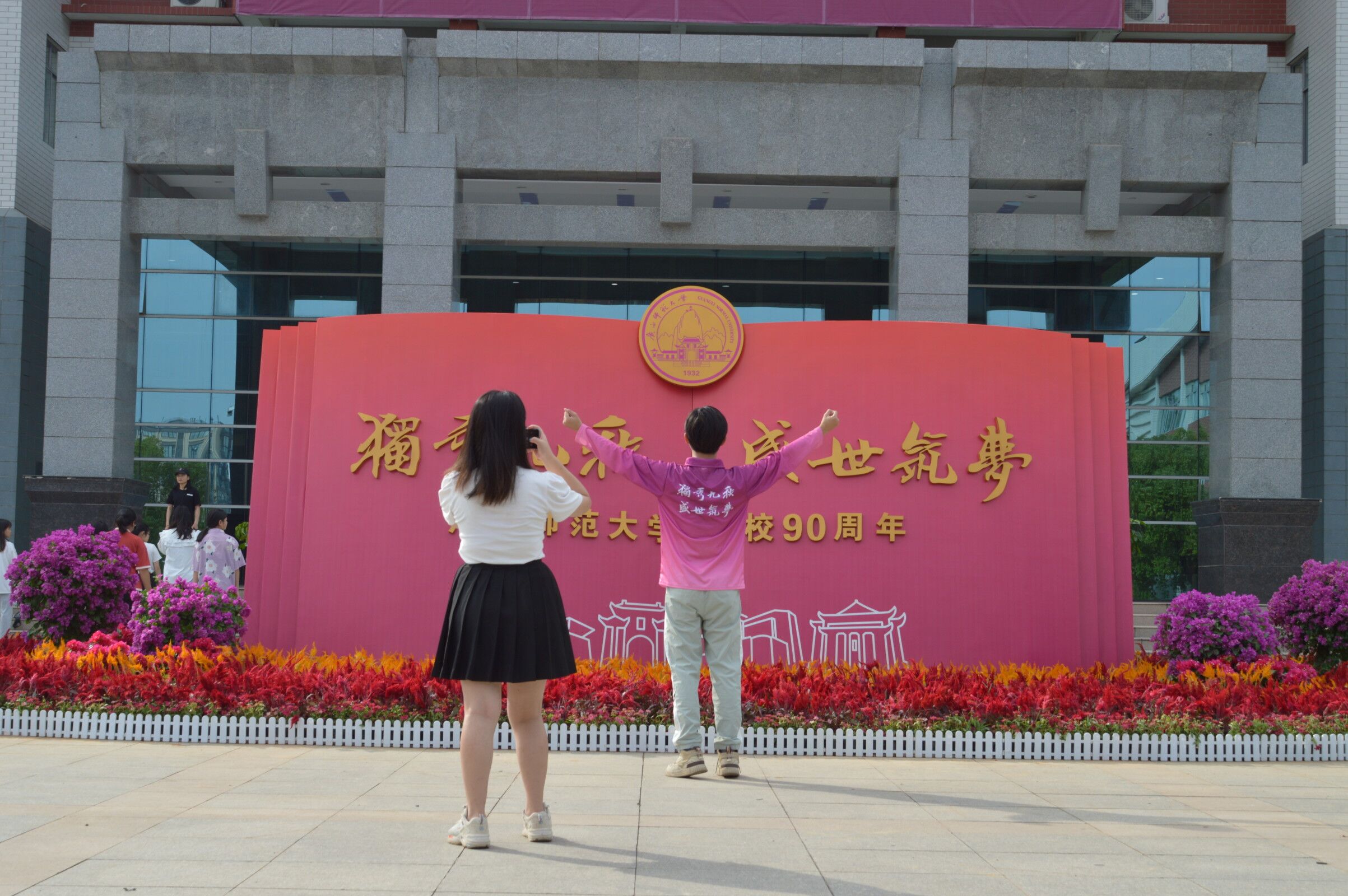 打卡美景，祝福母校繁荣昌盛。鲜花簇拥的书形雕塑象征着广西师大立德树人的使命担当。师大学子站在雕塑前张开双臂与之合影，记录青春时刻的同时也是为母校的九十岁生日送上祝福。按下快门，定格的和师大一起筑梦的美好心愿。.jpg