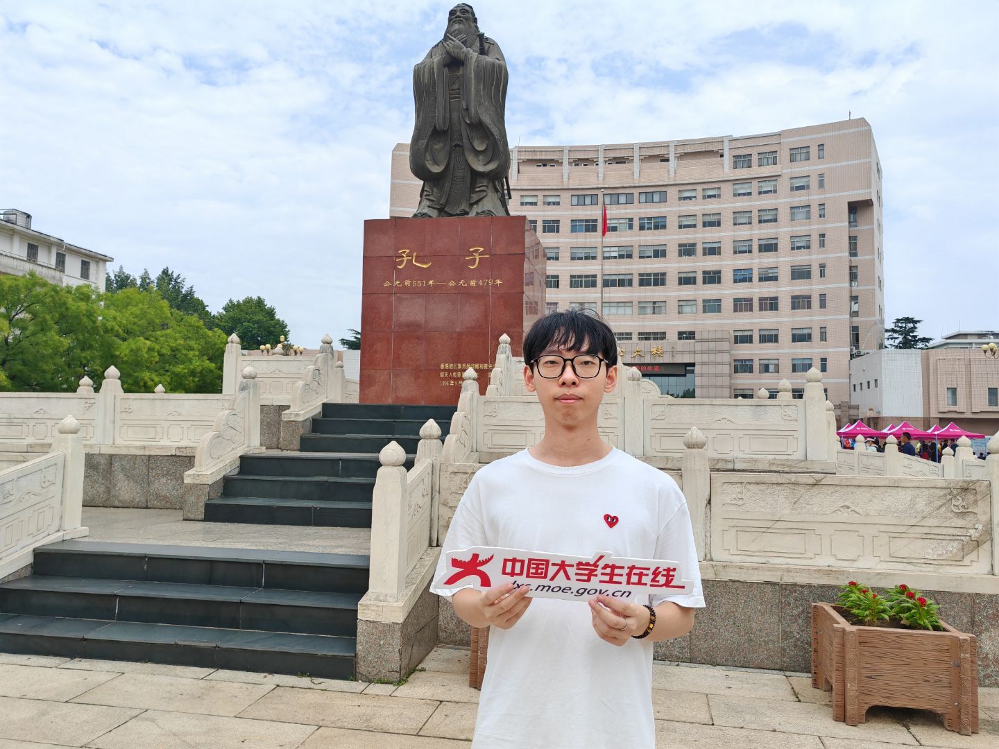 新生拿着中国大学生在线牌子在孔子像前