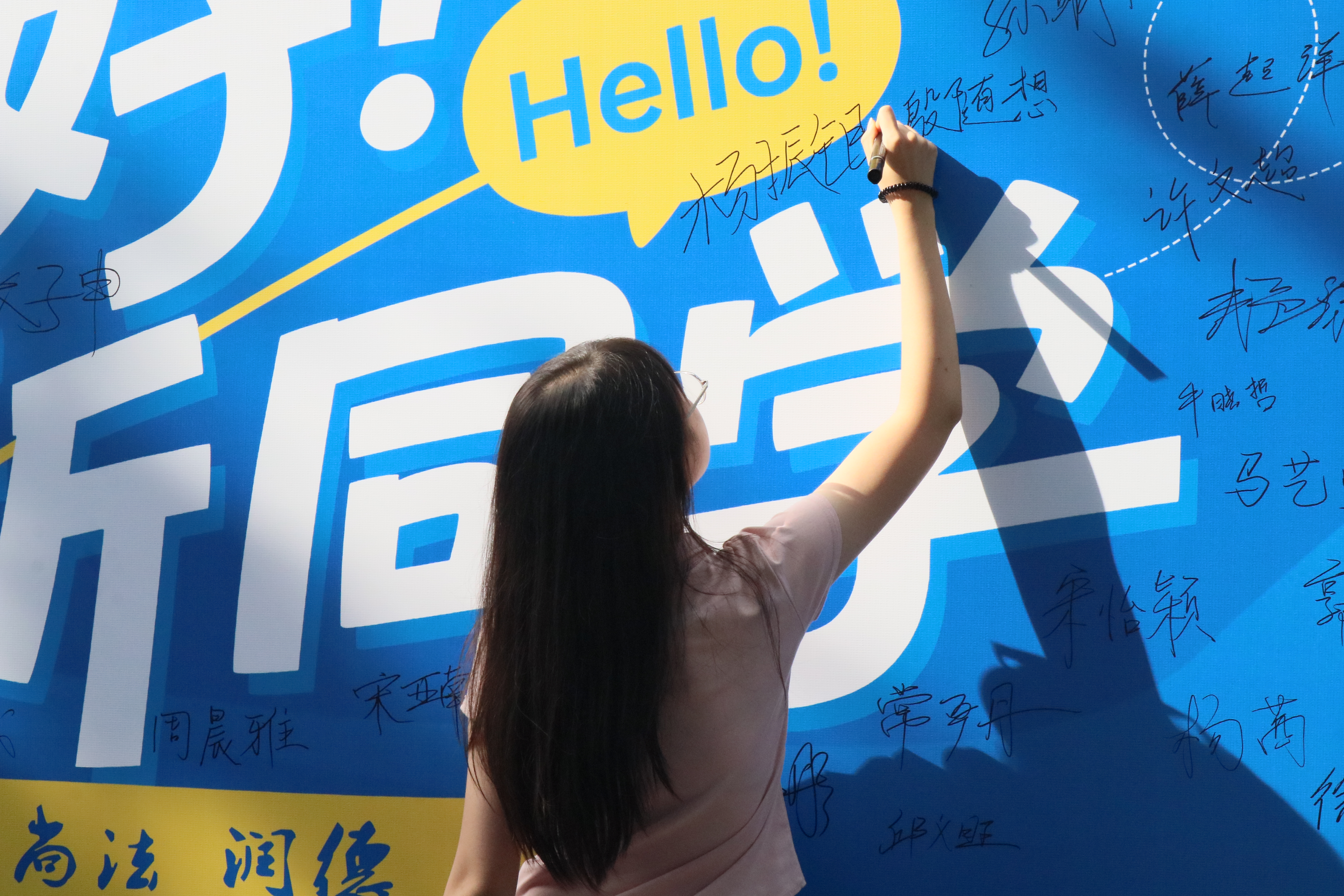 新生在 “你好新同学” 签名背景板上签下自己名字，留下入校的第一份纪念