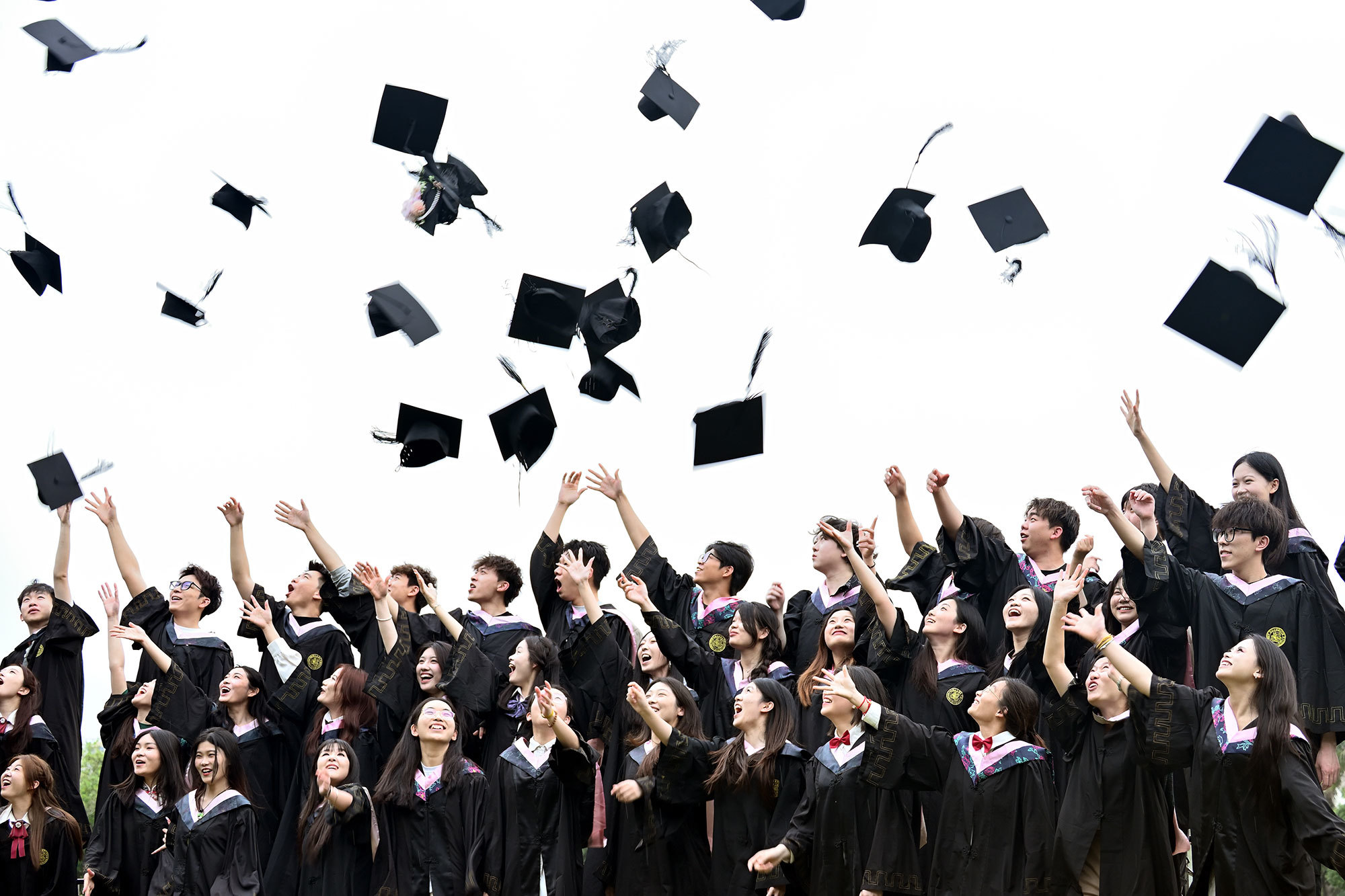 三十只手同时松开，学士帽腾跃成云，欢呼声惊飞树梢的鸟儿。有人仰头高喊：“别忘了我！”那尾音被风揉进蓝天里。镜头咔嗒，定格满屏笑脸。滚烫情谊在帽影翩跹中，酿成永不褪色的盛夏记忆。（摄影：曾言尘）