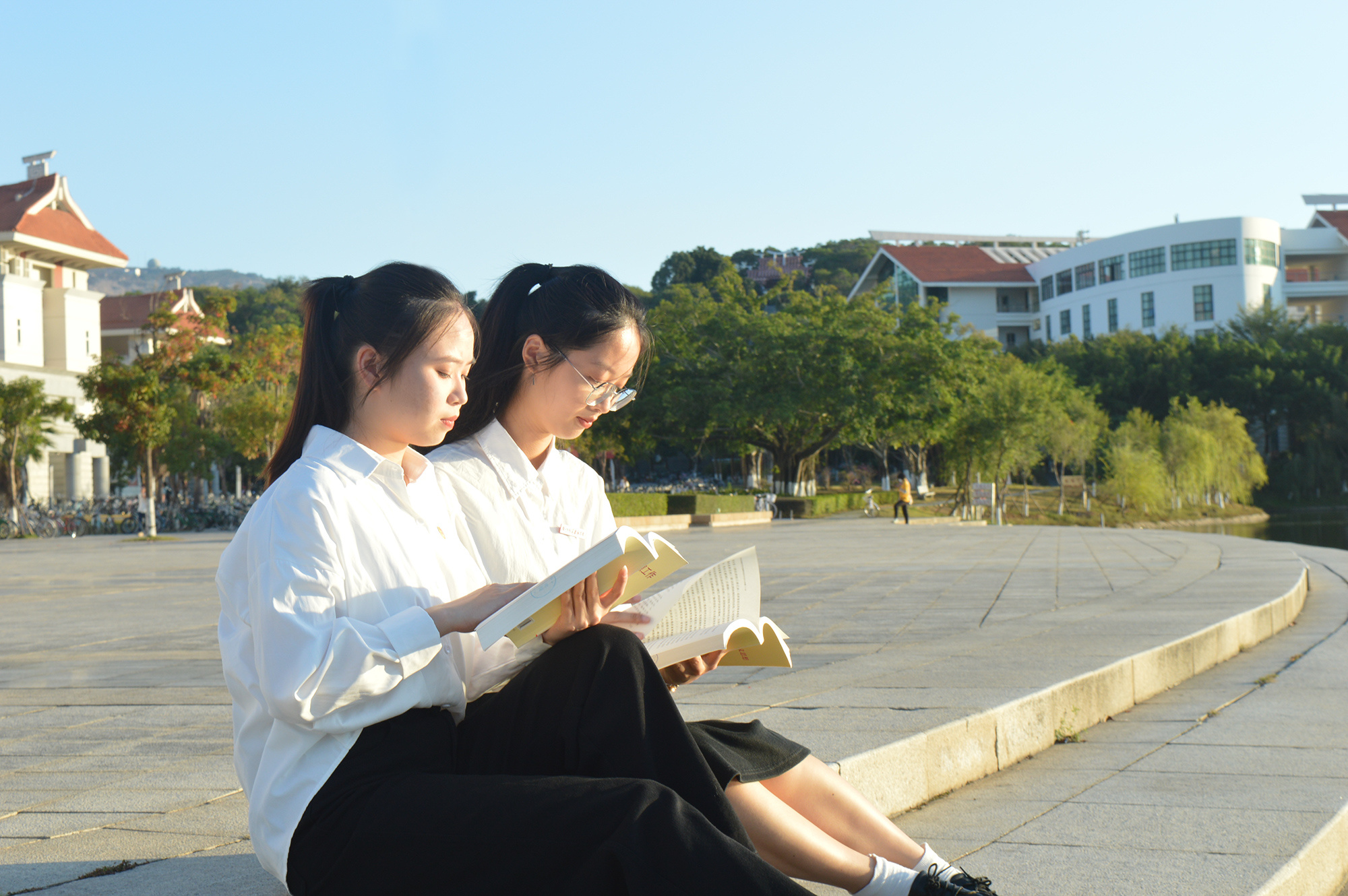 入党积极分子（左）带着同学一起在图书馆前的湖畔阅读新经典书籍